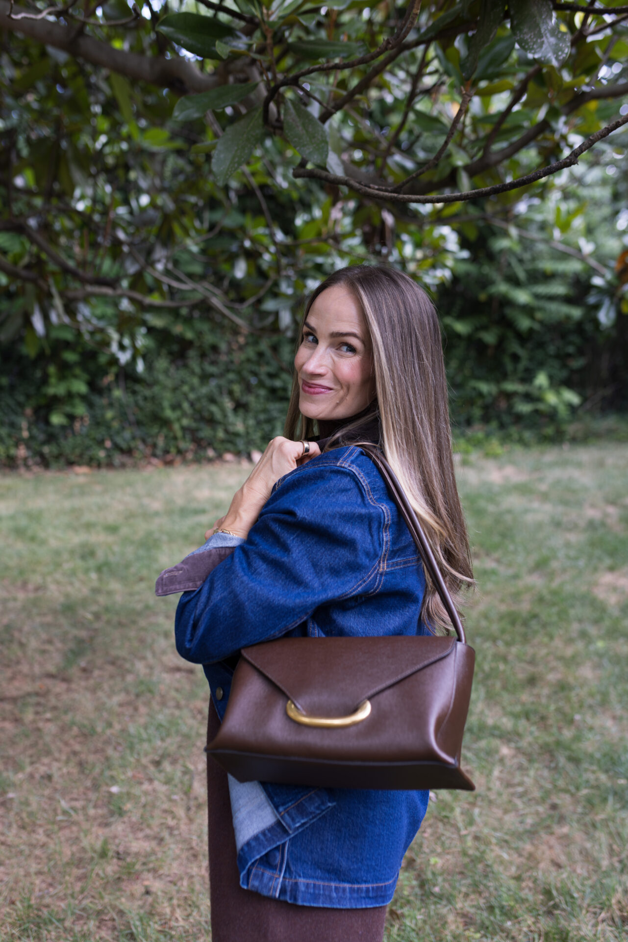 TeriLyn Adams wearing marine layer barn jacket over brown sweater dress with Veneto shoulder bag.