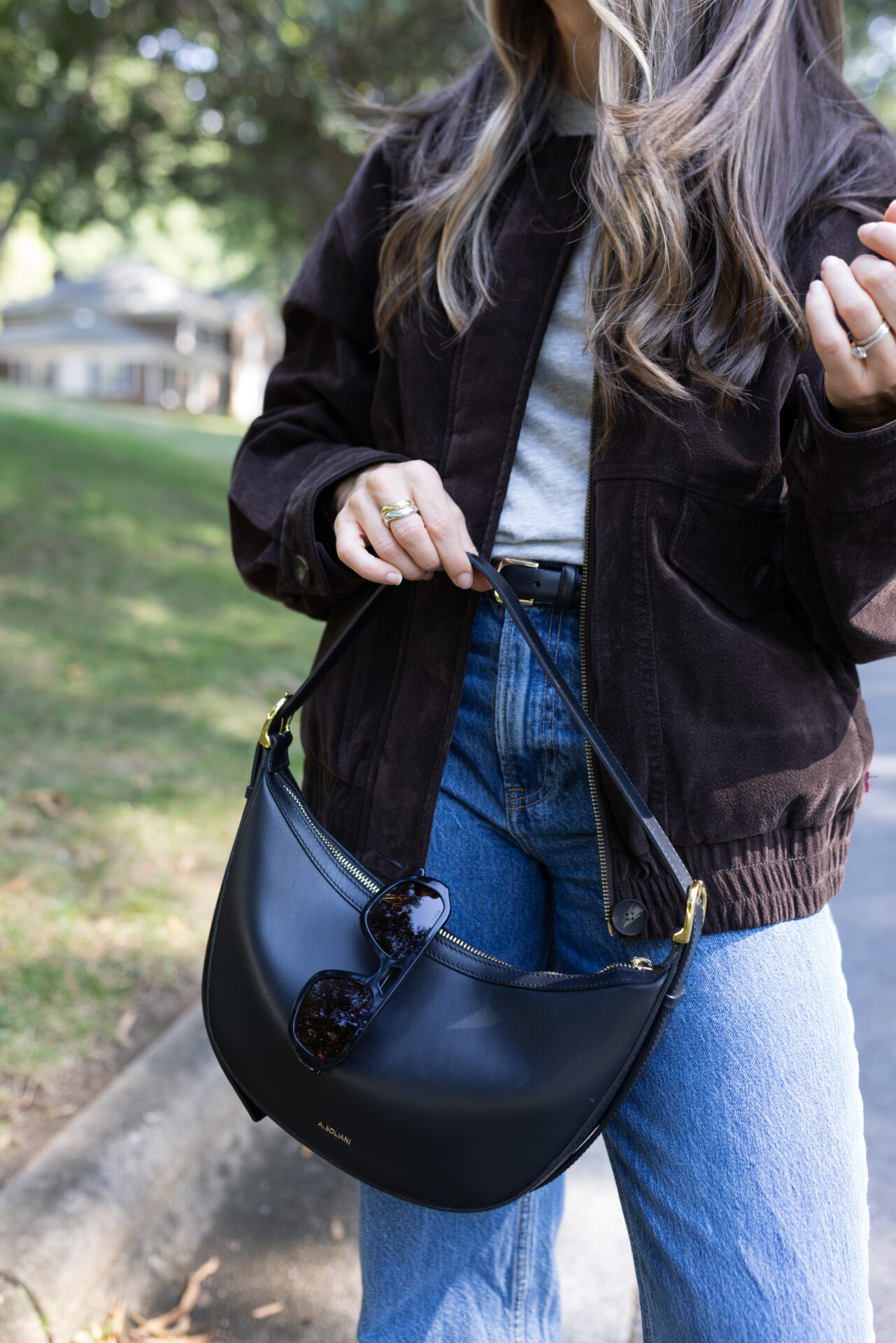 TeriLyn Adams wearing jeans and Levi's suede bomber jacket with black leather purse.