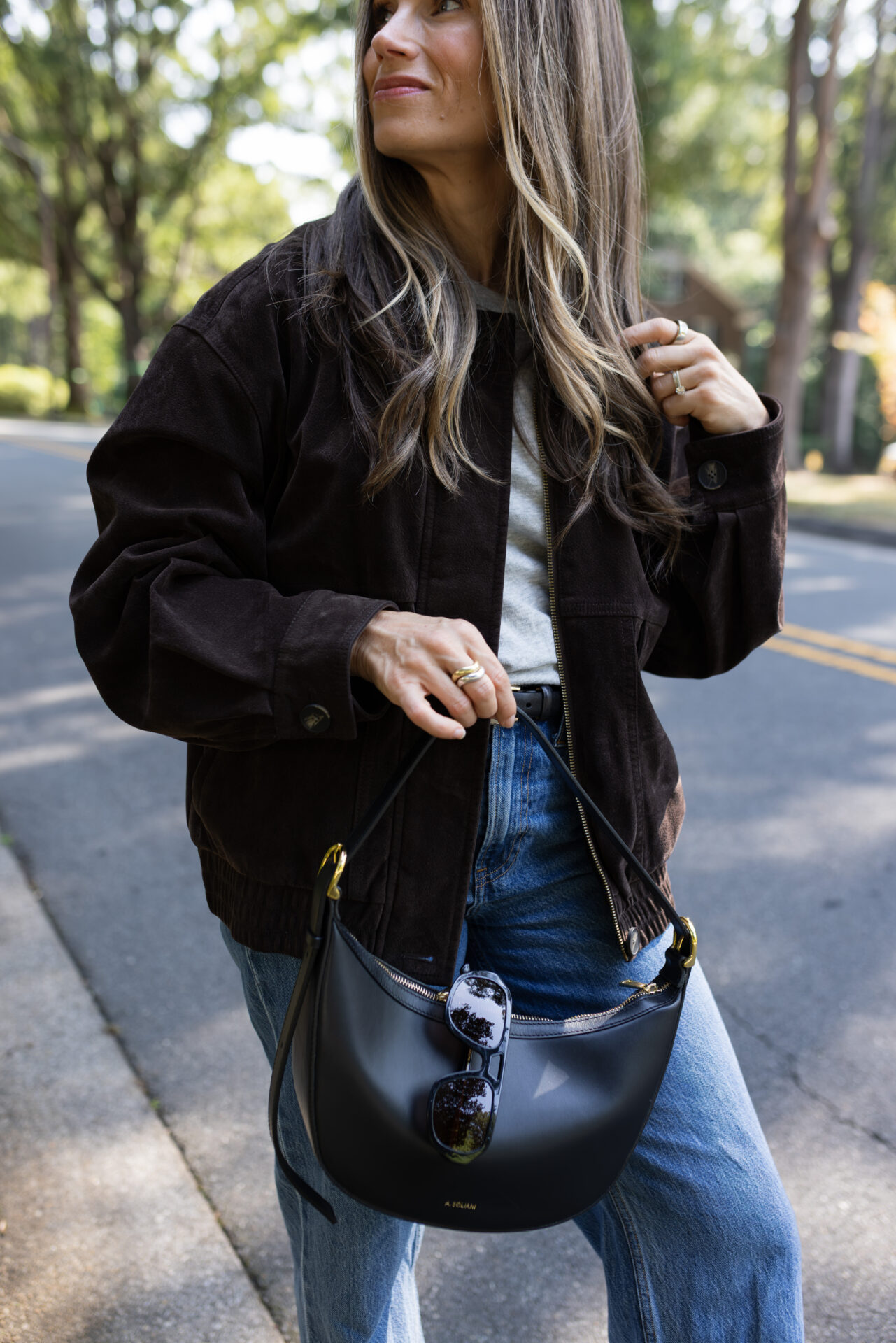 TeriLyn Adams wearing jeans and Levi's suede bomber jacket with black leather purse.