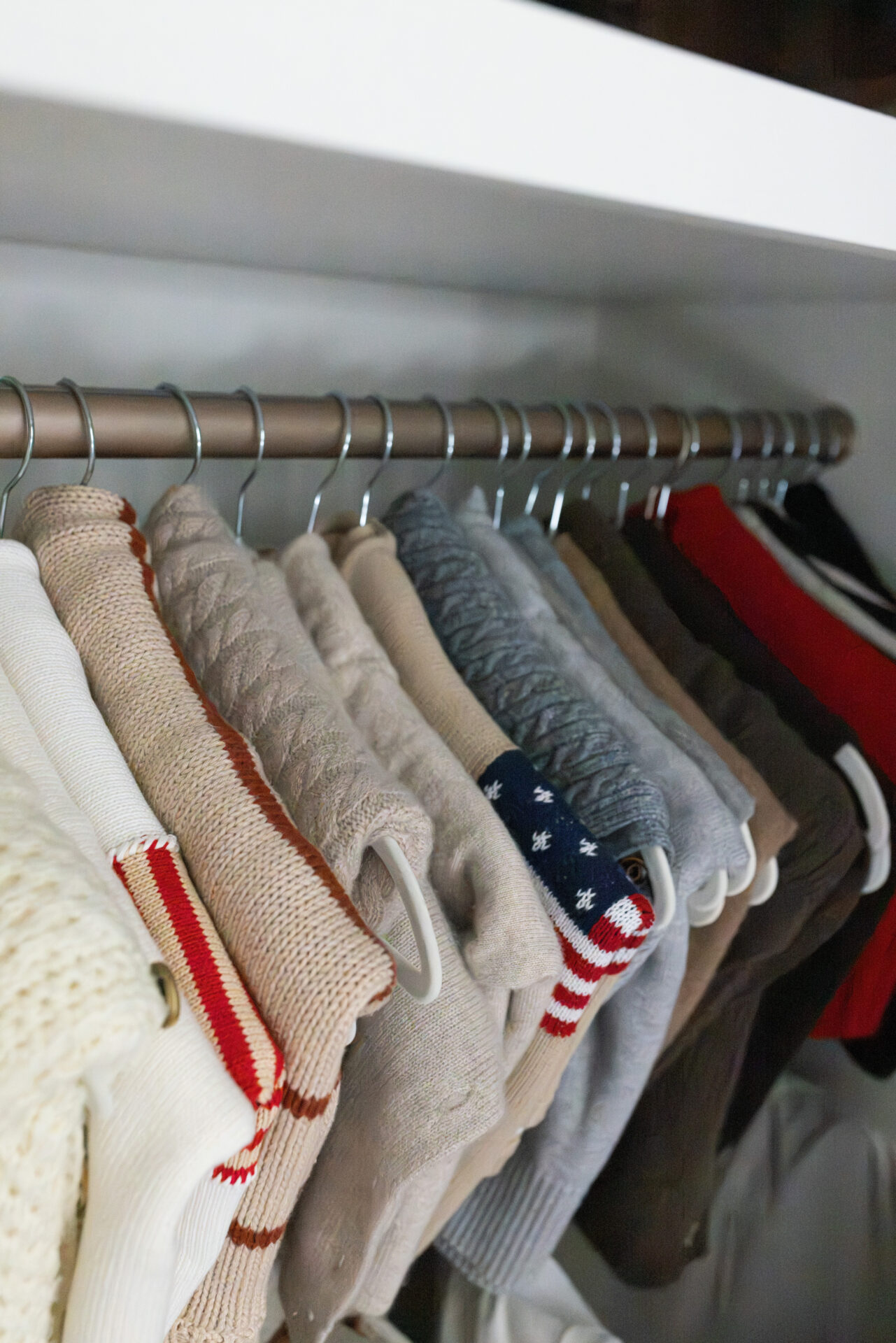 sweaters lined up in closet for fall capsule wardrobe