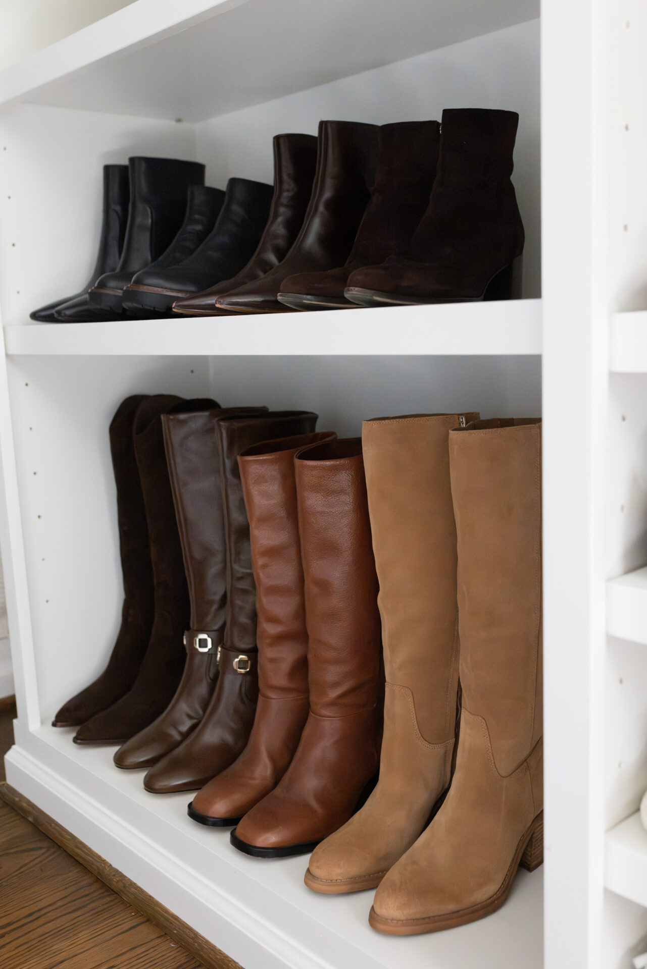Black and brown leather ankle boots above knee-high boots in brown suede, leather, cognac, and tan on closet shelves
